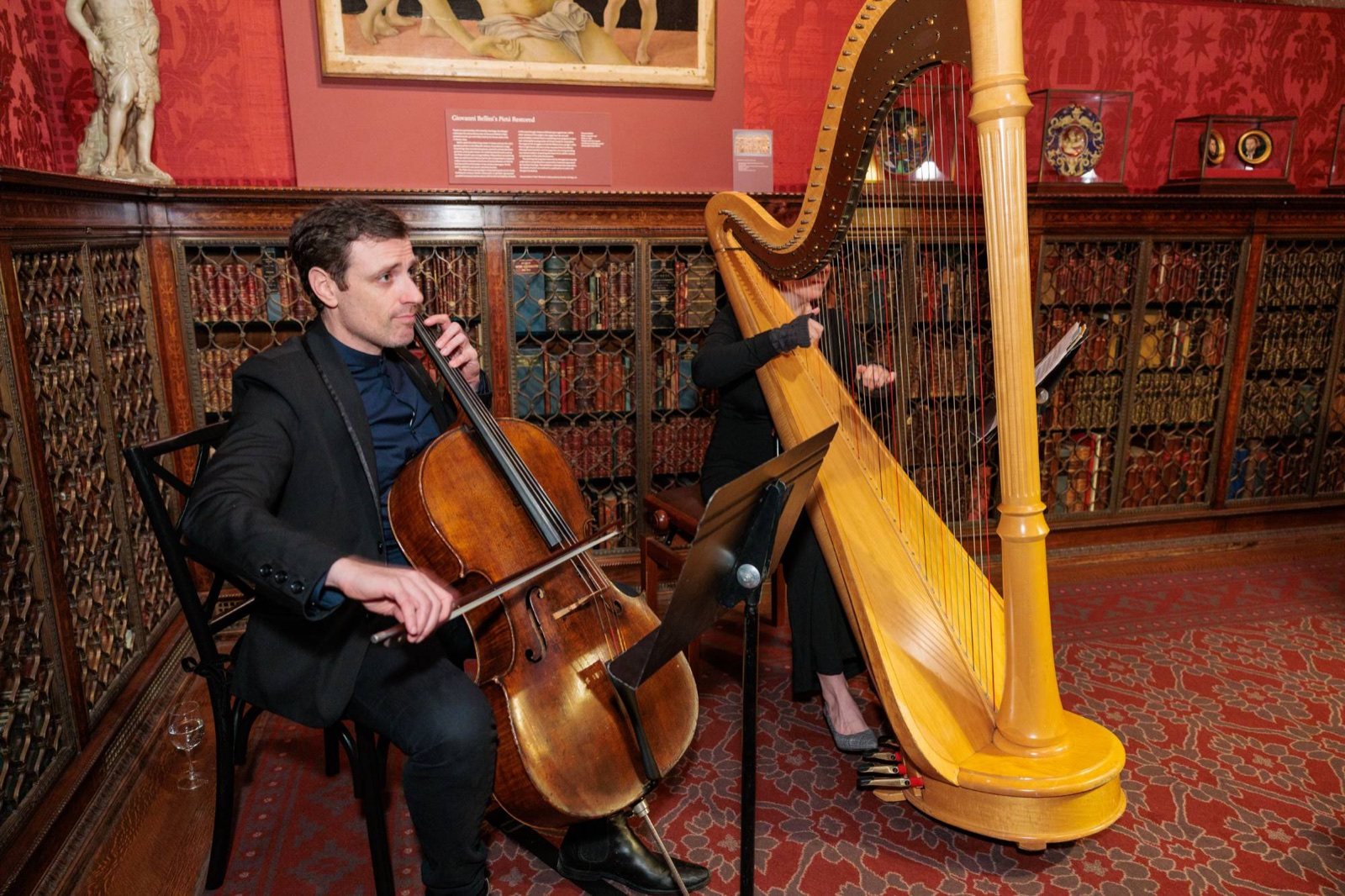 A cellist and harpist playing in the red library