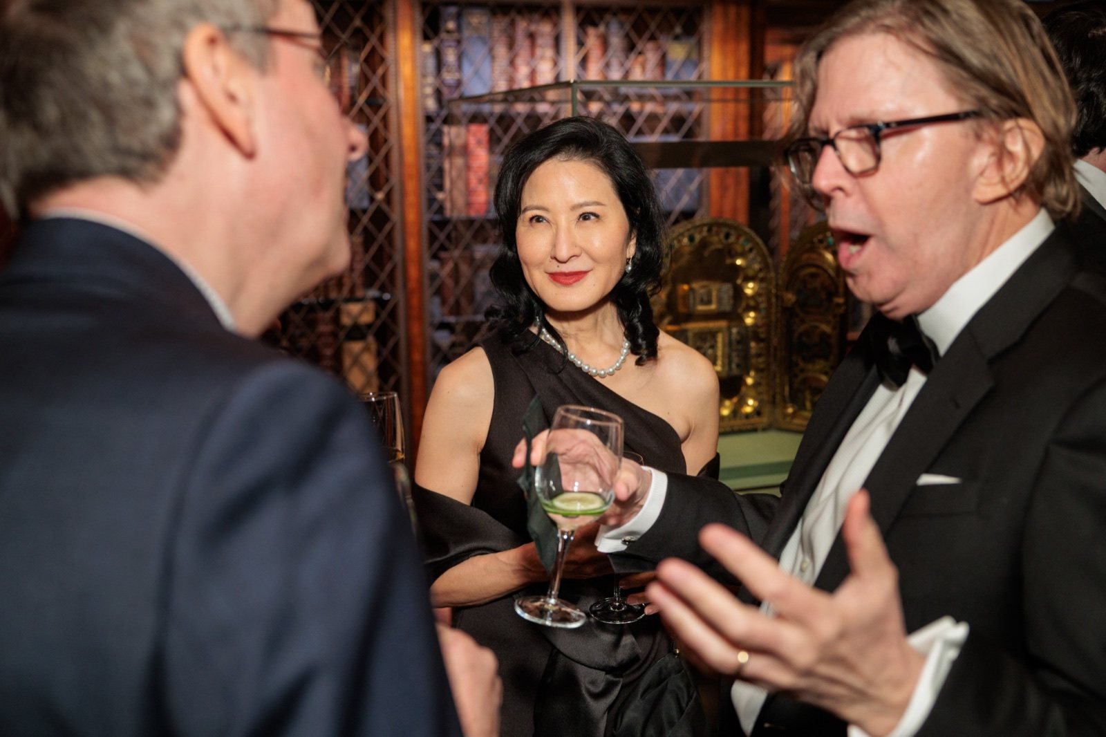 A guest with a drink among the library bookcases