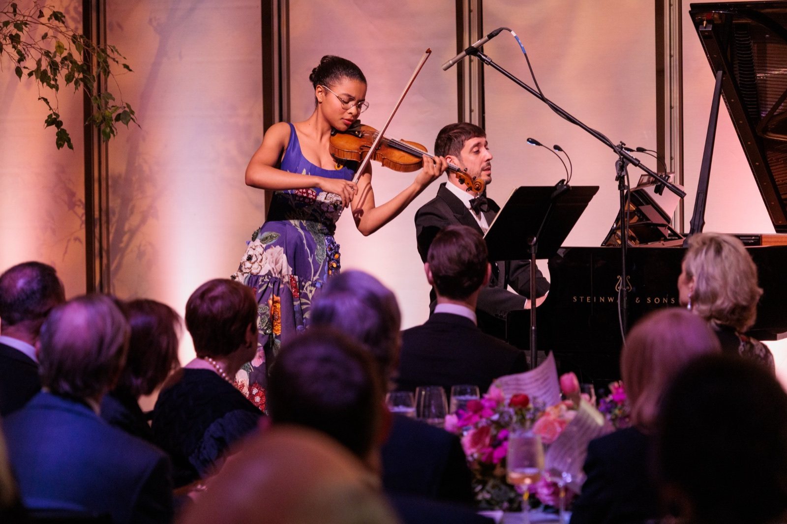 A violinist and pianist performing for dinner guests
