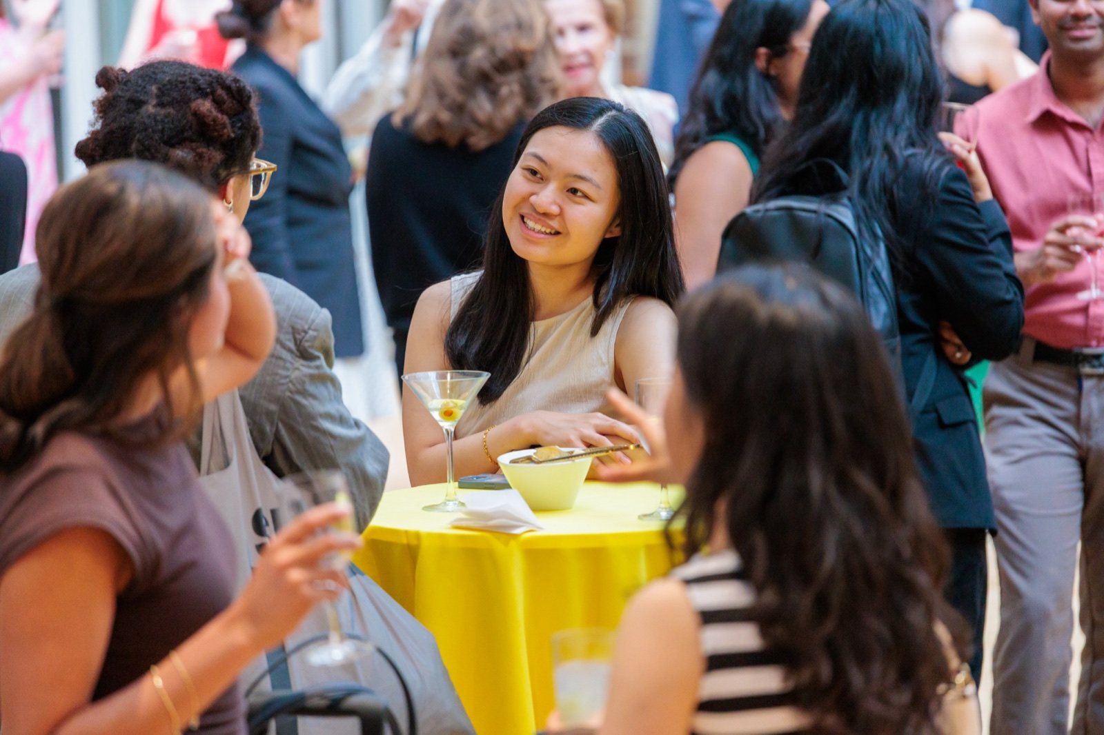 A guest with a martini at a yellow cocktail table